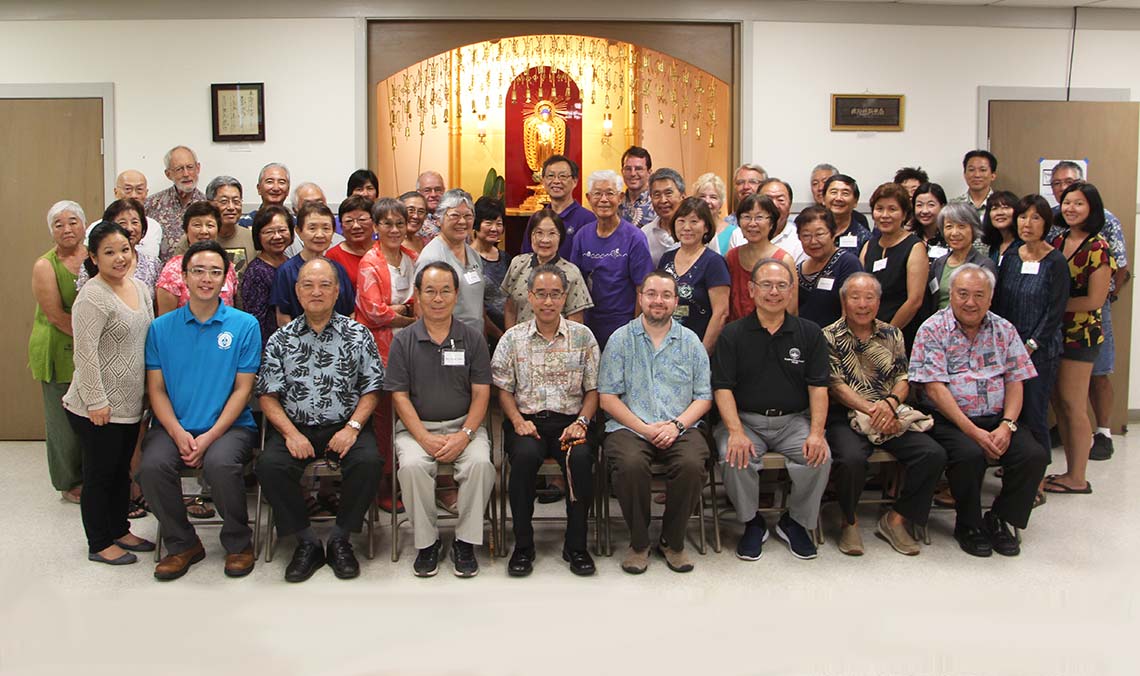 Bishop, speaker, ministers, and attendees in a group photo before the alter in the Buddhist Study Center classroom